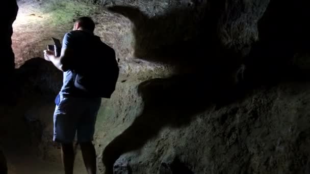 Young tourist scientist studies the state of the cave. — Stock Video