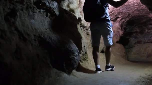 Ung turist forskare studerar tillståndet i grottan. — Stockvideo