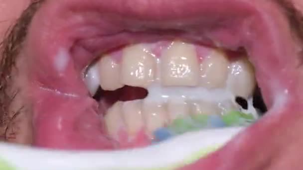 Dental hygiene - a person holds a toothbrush with toothpaste in his hand and brushes his teeth. — Stock Video