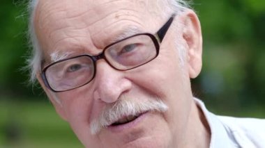 Gözlüklü ve dişlek bir gülümsemesi olan yakışıklı yaşlı bir adamın yüzünü kapat..