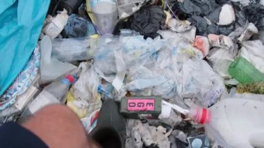 Bir adam çöplükte yürüyor, plastik atık için çevresel bir felaket..