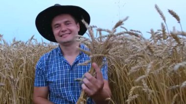 Ellerinde buğday kulakları olan mutlu bir çiftçi. Çiftçi hasatta seviniyor.