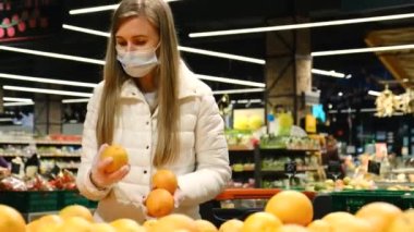 Avrupalı bir kadın hipermarkette portakal seçer..