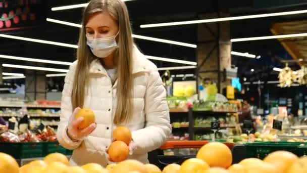 Una mujer europea elige naranjas en un hipermercado. — Vídeos de Stock