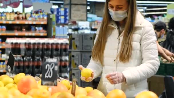Una chica rubia elige naranjas en el mercado. — Vídeos de Stock