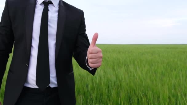 En man i svart kostym visar en tumme upp, ett tecken på njutning — Stockvideo