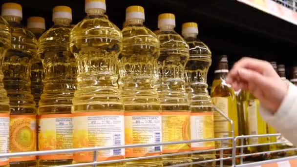 Una joven que recoge una botella de aceite de oliva en el supermercado. — Vídeos de Stock