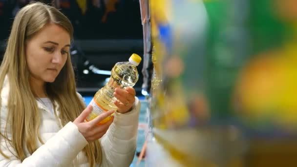 Una mujer elige aceite vegetal en un supermercado. — Vídeos de Stock