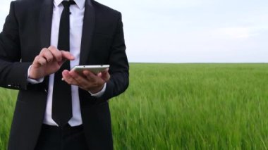 Bir adam elinde tabletle bir arpa mahsulünü inceliyor..