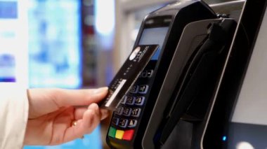 Kredi kartı terminali kullanarak ödeme yapan bir kadının elleri.,