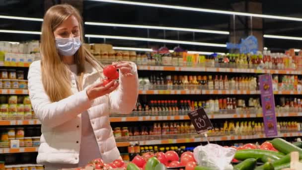 Een vrouw kiest rijpe sappige tomaten in de supermarkt — Stockvideo