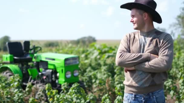 Junger glücklicher Bauer freut sich über seinen neuen Traktor. Mann auf Feld neben grünem Mini-Traktor. — Stockvideo