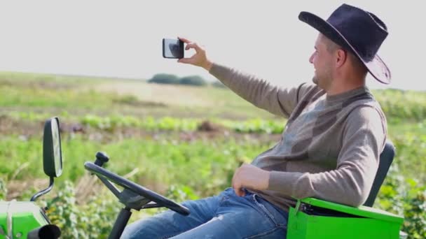 Glad landmand tager et selfie foto, mens han sidder på sin traktor. – Stock-video