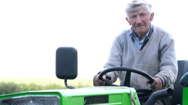 Retrato franco de un granjero mayor sentado en un tractor. — Vídeos de Stock