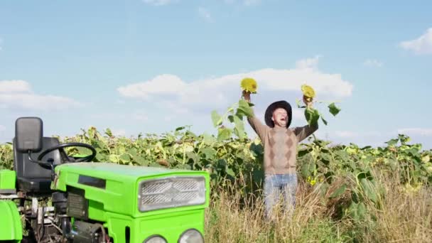 Dorpswerker is gelukkig en danst met zonnebloemen in zijn handen — Stockvideo