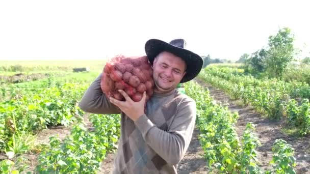 Ein junger Bauer hält einen Sack Kartoffeln in der Hand. — Stockvideo