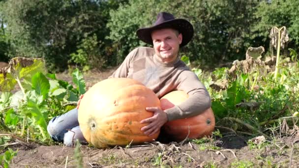 Agricultor con calabazas, joven agricultor con calabazas abrazando una calabaza grande. — Vídeo de stock