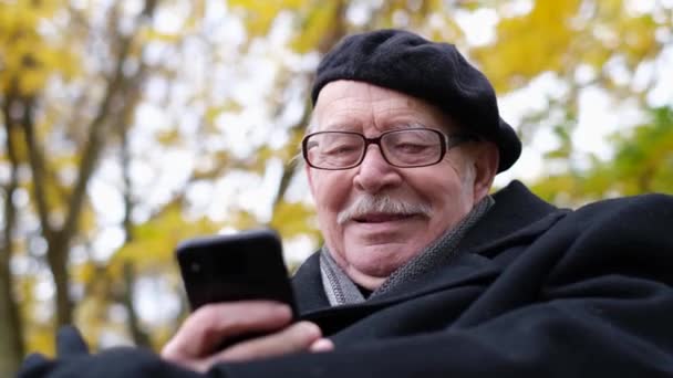 Boční pohled na pozitivní starý relax podzim město říjen park sedět na lavičce. — Stock video