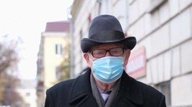 Koruyucu maskeli yaşlı bir dede şehrin sokaklarında yürüyor.