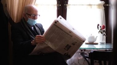 Maskeli emekli bir adam bir kafede oturur ve gazete okur..