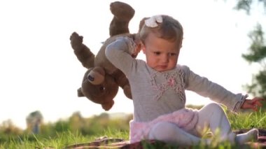 Sinirli bir çocuk yere yumuşak bir oyuncak ayı atar..