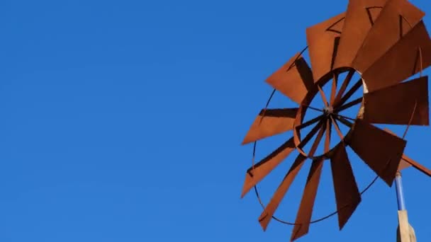 Las aspas del ventilador de la bomba de viento se mueven rápidamente contra el cielo azul. — Vídeos de Stock