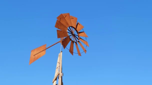 Retro fan of a wind pump moving fast against a blue sky. — Stock Video