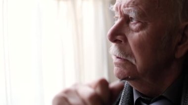 Pencereden dışarı bakan yaşlı bir adamın yakın plan yüzü..