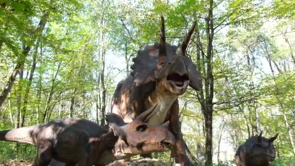 Dinosaurio entre los árboles del parque. Modelo robótico en la exposición — Vídeo de stock
