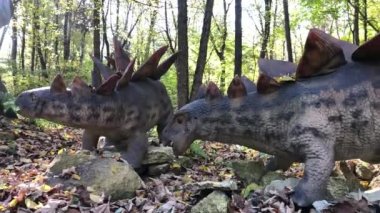 Çocuklar dinozor heykelleriyle park ederler.. 