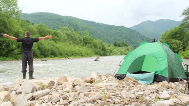 Turista postavil zelený stan poblíž horské řeky. — Stock video