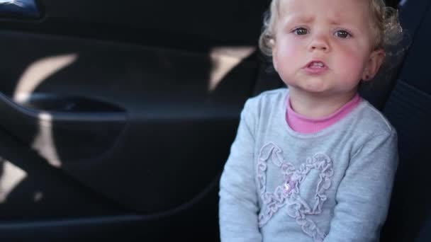 Mała dziewczynka bije brawo w dłoni, siedząc w samochodzie. — Wideo stockowe
