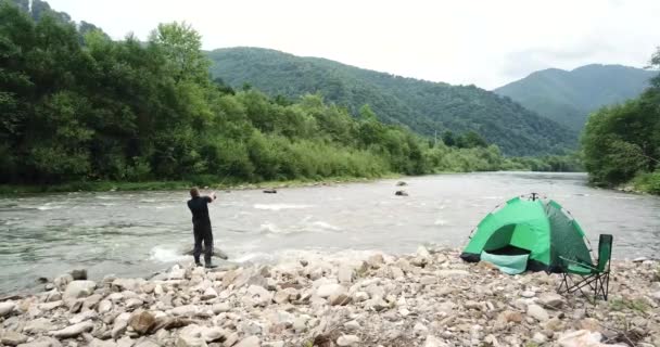 Pesca. Pesca en las tierras altas. Pescador en la orilla de una montaña, río rápido. — Vídeos de Stock