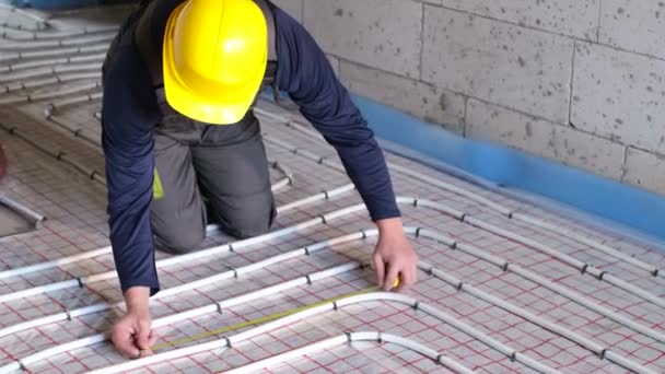 Handwerker verlegt Rohre für Fußbodenheizung. — Stockvideo