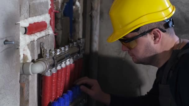 Um encanador macho instala aquecimento em uma casa recém-construída. — Vídeo de Stock