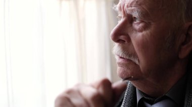 Pencereden dışarı bakan yaşlı bir adamın yakın plan yüzü..