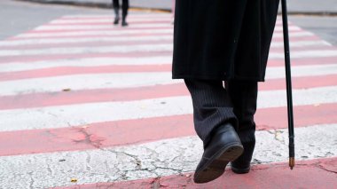Yaşlı büyükbaba yaya geçidinden geçiyor. Bacaklarının arkasını görüyor..