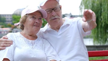 Parktaki bankta oturan mutlu yaşlı çift.