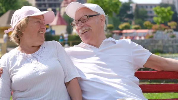 Alegre pareja de ancianos sentados en un parque de verano y divertirse. —  Fotos de Stock