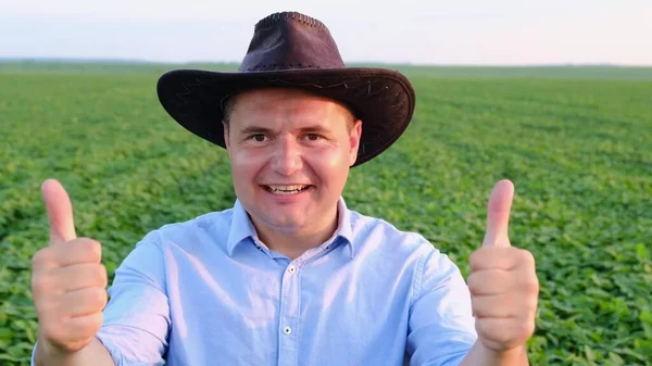 Portret van een jonge boer in een blauw hemd die zijn duimen omhoog steekt — Stockfoto