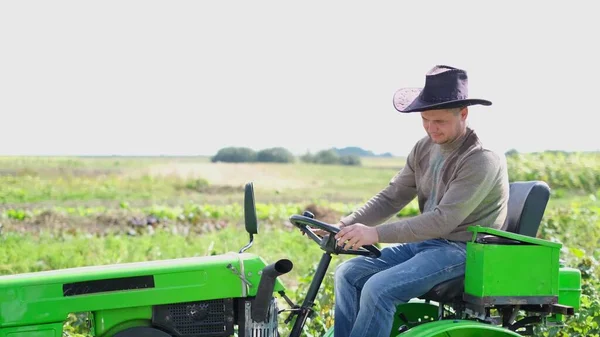 Genç bir çiftçi traktörde oturur ve kameraya mutlu bir şekilde gülümser.. — Stok fotoğraf