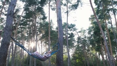 Çam ormanında hamakta dinlenen bir kız..