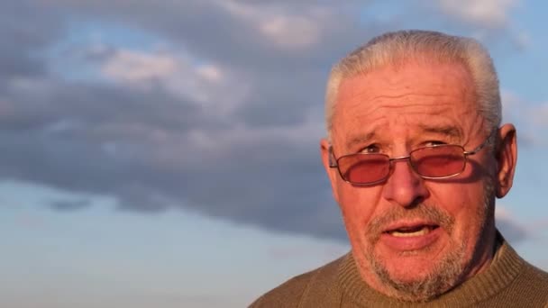 Um velho homem de cabelos grisalhos de óculos de sol ri feliz — Vídeo de Stock