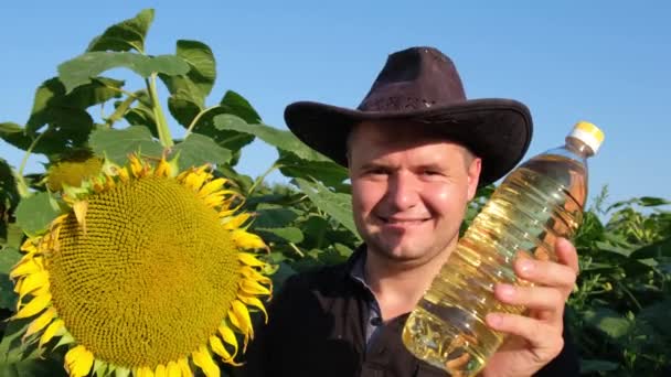 Vegetable oil in the hands of the farmer on the background of sunflowers. — Stock Video