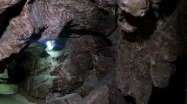 El feneriyle aydınlatılmış derin bir mağara..