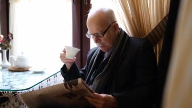 Yaşlı bir emekli kahveyle gazete okur..