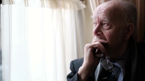 Sluit maar af. Senior trieste oudere man in pak kijkt uit het raam.. — Stockvideo