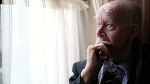 Close up . Senior sad elderly man in suit looking out the window.. — 图库视频影像