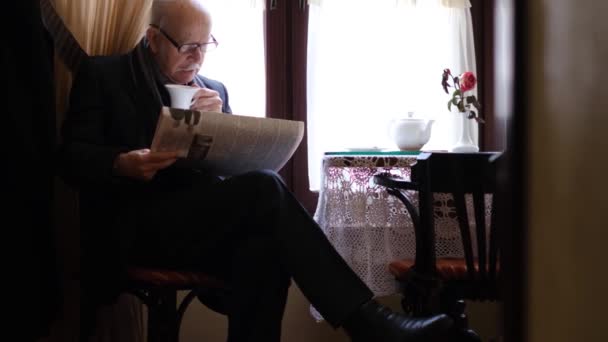Ανώτερος άνθρωπος με ένα φλιτζάνι καφέ διαβάζοντας μια εφημερίδα στον ελεύθερο χρόνο του. — Αρχείο Βίντεο