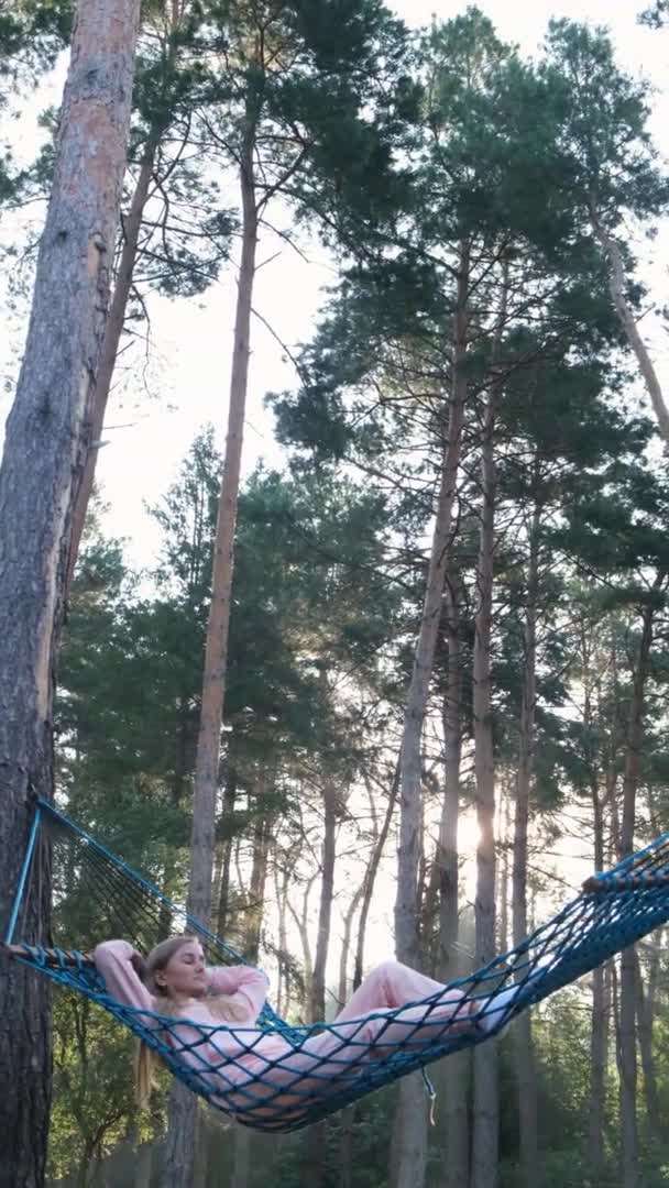 Vidéo verticale. Femme dormant dans un hamac dans la forêt printanière. — Video